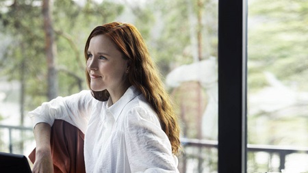 Kvinna vid skrivbordet med panoramafönster i bakgrunden.