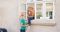 två flickor pratar genom ett fönster