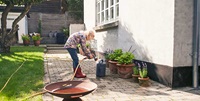 kvinna vattnar blommor i tärdgård