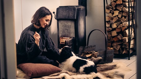 Kvinna med hund vid kamin