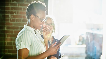 två kvinnor tittar på tablet