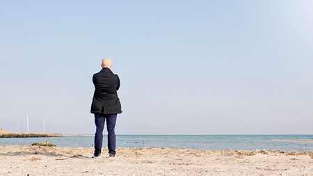 man står på strand och blickar ut över havet