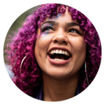 Person med lila lockigt hår och stora örhängen utomhus.