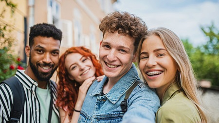 Fyra unga personer står nära varandra utomhus och tar en selfie.