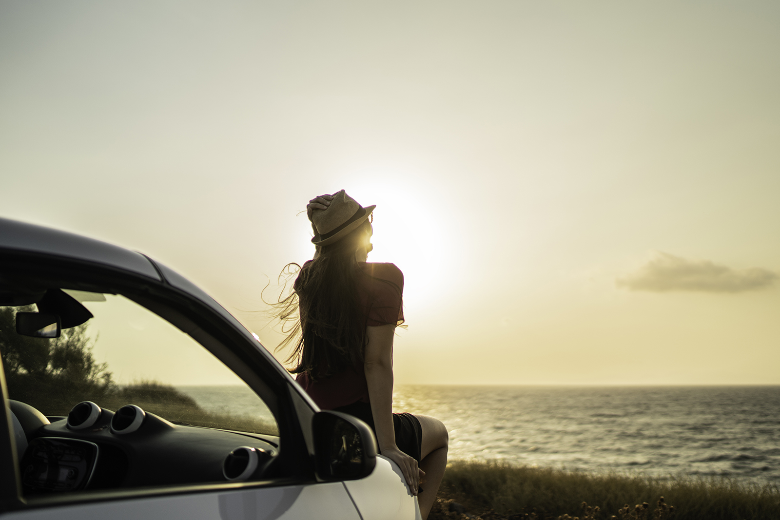 kvinna sitter på motorhuven och njuter av solnedgång
