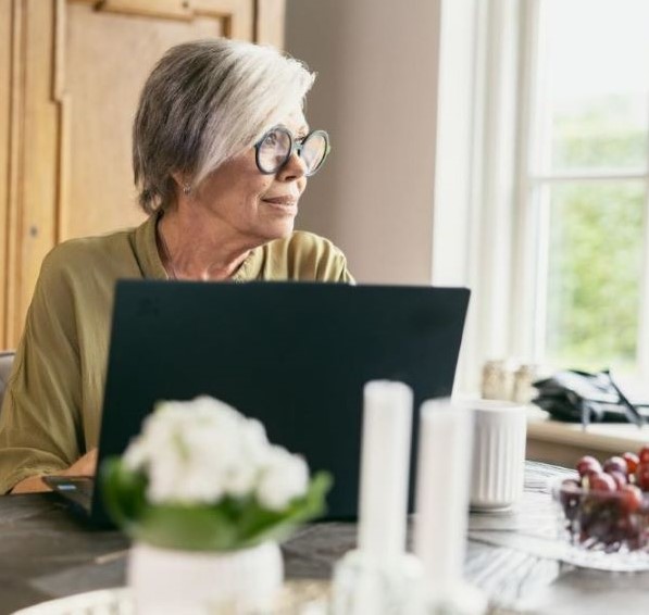 kvinna siter vid köksbord vid dator