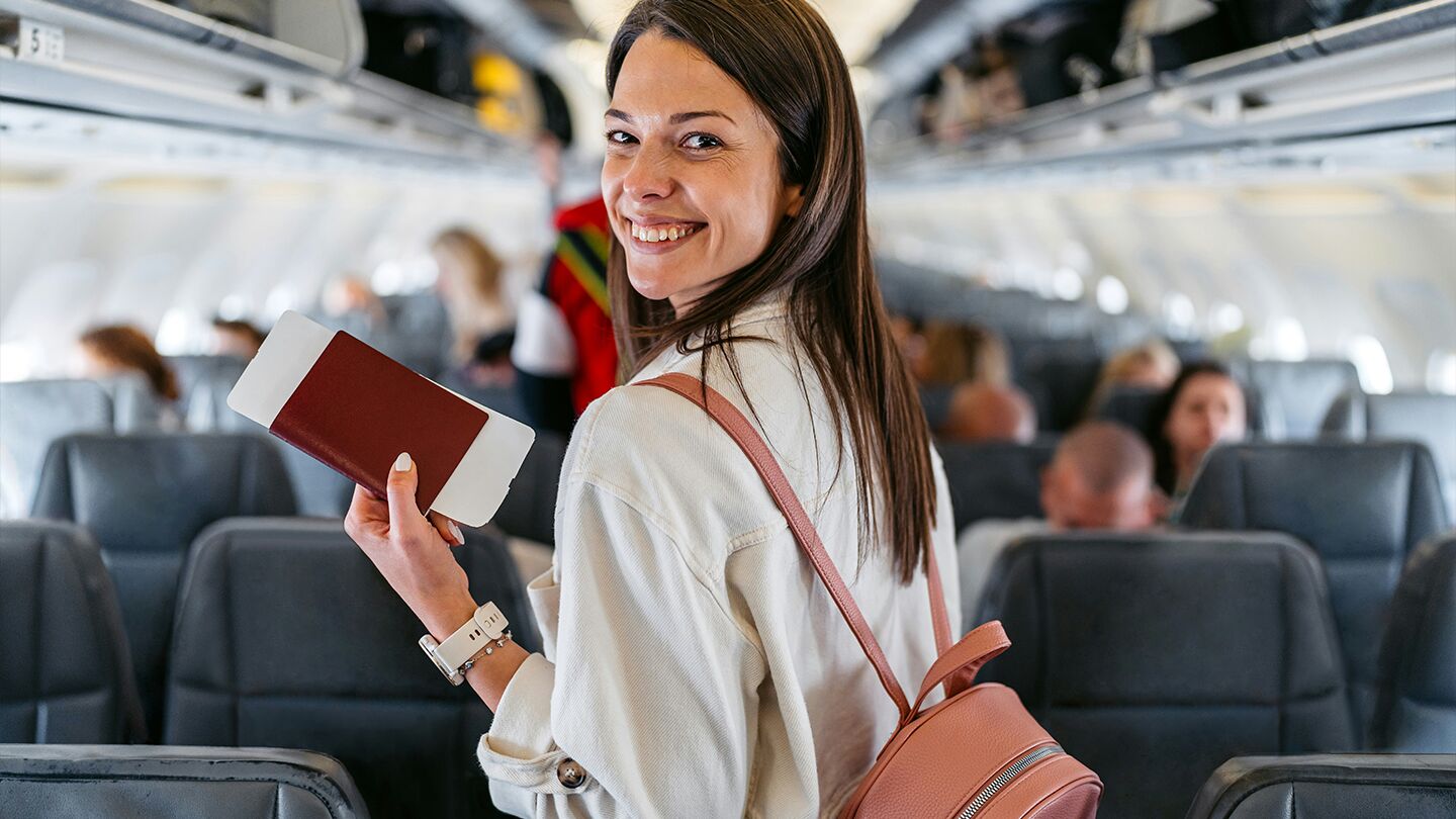 Kvinna håller i ett pass ombord på ett flygplan.
