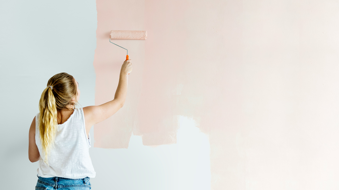 Person målar en vägg inomhus.
