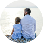 Pappa med dotter sitter på en strand