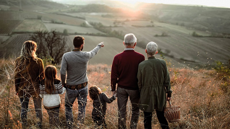 Familj blickar ut över ett landskap i solnedgång.