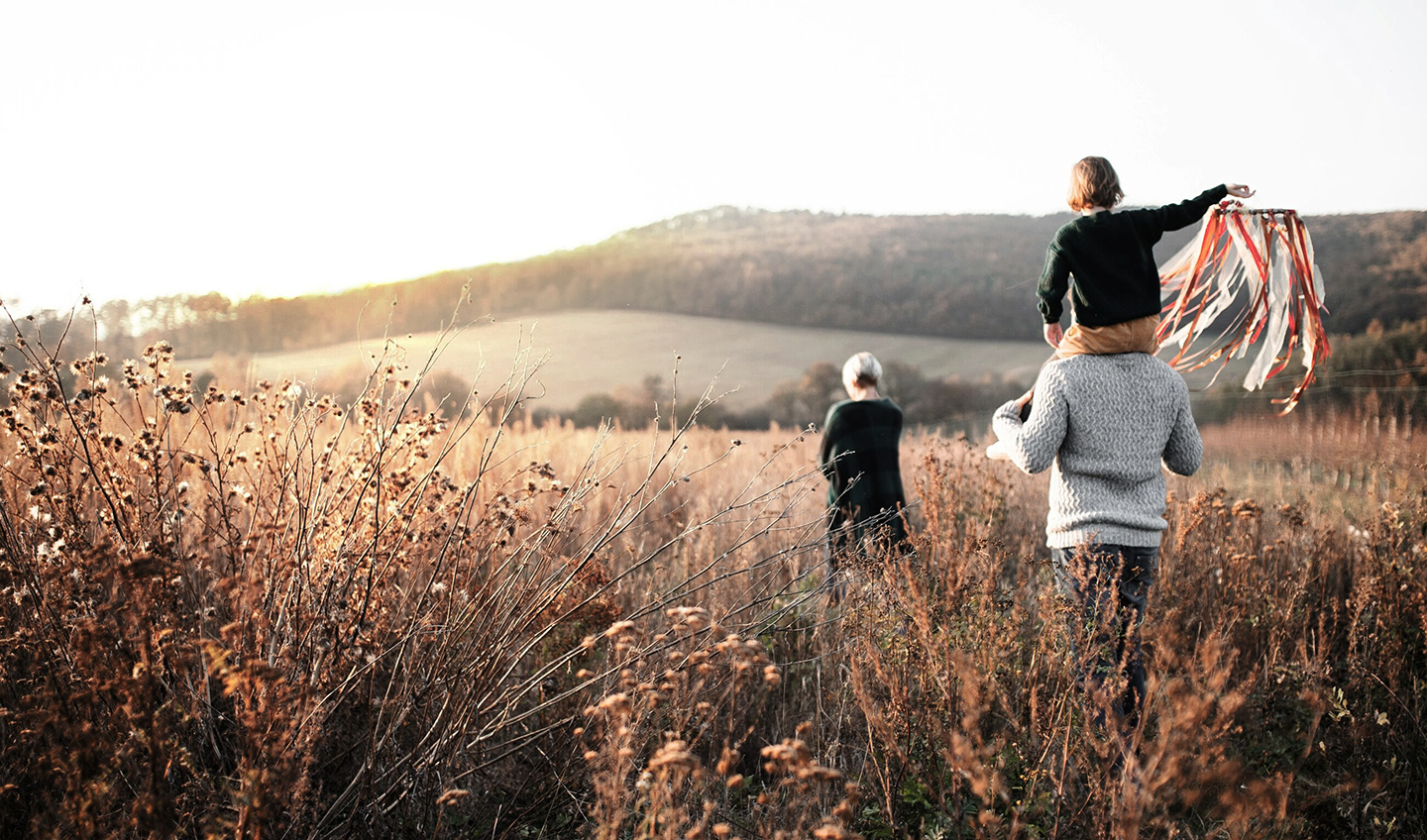 Familj som promenerar i en höstig äng.