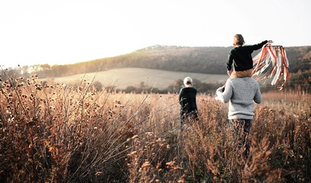 Familj som promenerar i en höstig äng.