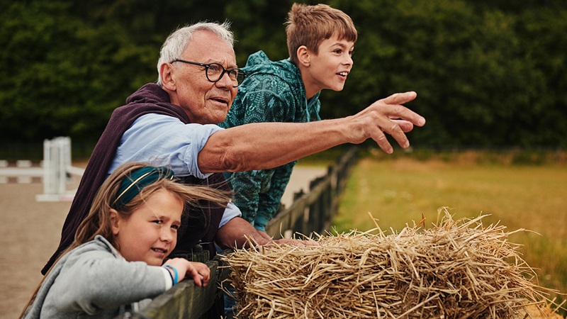 Äldre man med barnbarn på gård