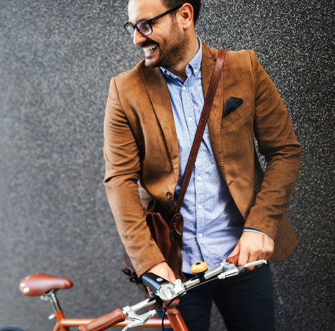En person i kavaj står vid en cykel mot en grå bakgrund.