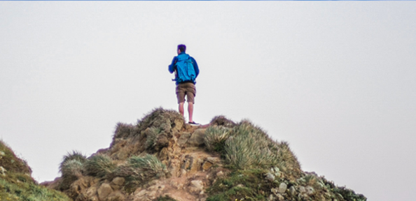 Person står på en klippa och blickar ut.