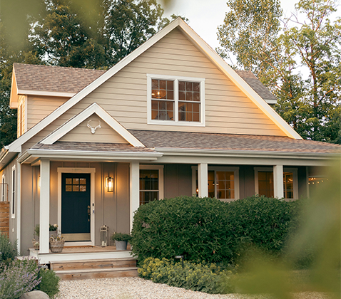  Ett charmigt hus med två våningar, en välkomnande veranda och en blå ytterdörr. 