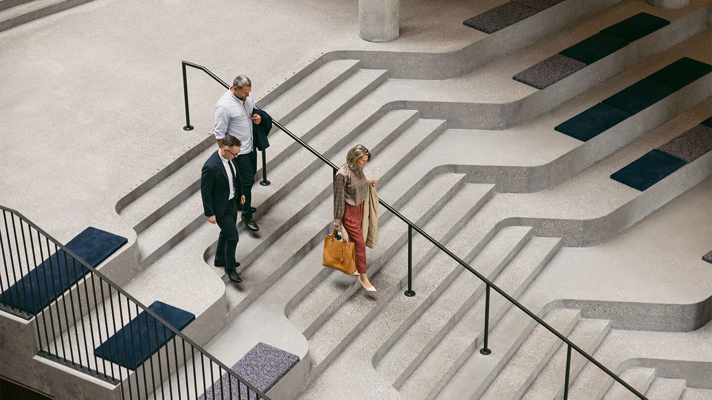 Personer går nerför moderna trappsteg med sittplatser vid sidan om.