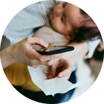 Närbild på händer som skriver på ett papper med en penna och håller i ett spädbarn.