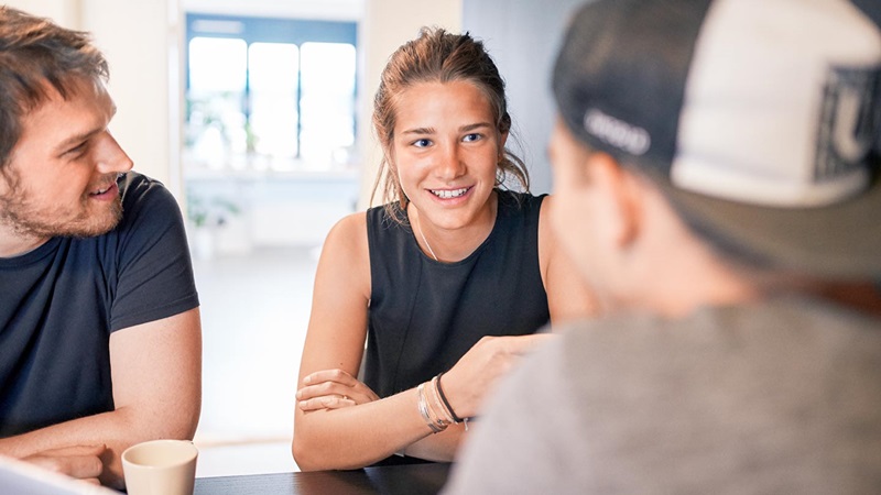 tre studenter sitter runt bord