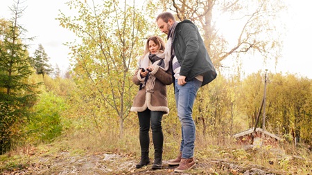 man and woman with phone in woods
