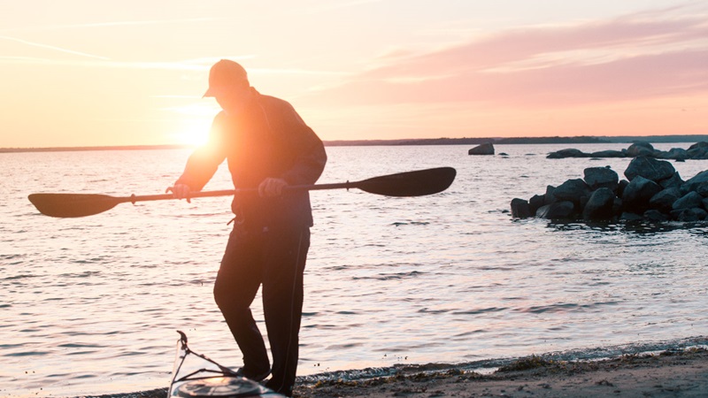 Man på strand med kajak