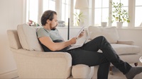 Man reading business documents on sofa