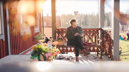 man på veranda med surfplatta