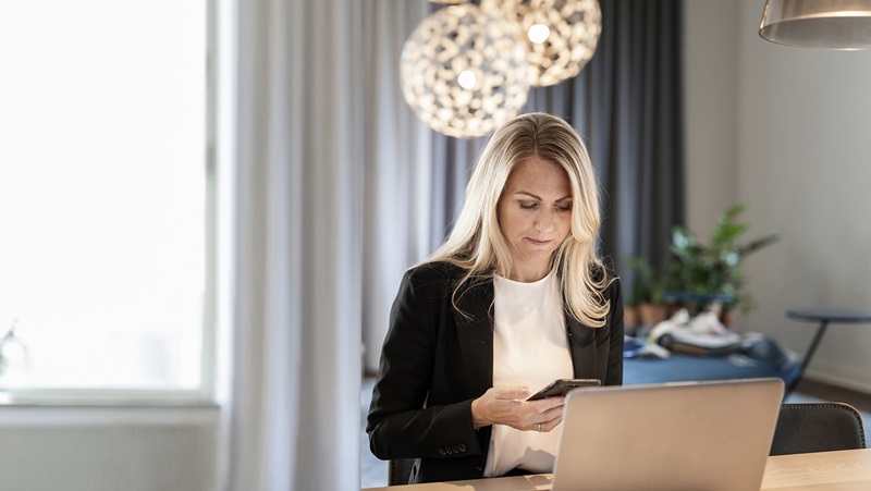 kvinna sitter vid bord med mobil